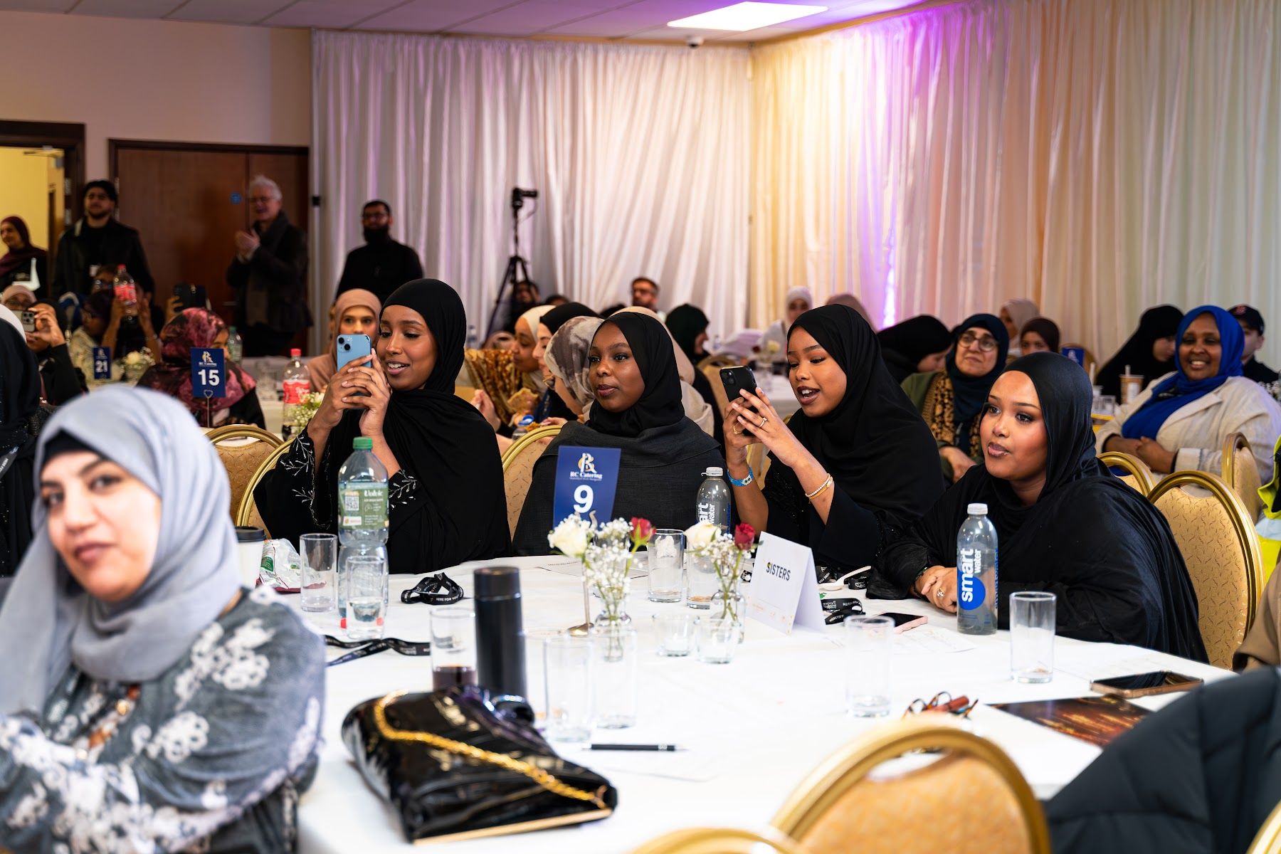 Guests seated at round tables during the 2025 Awards dinner, filming the stage on their phones.