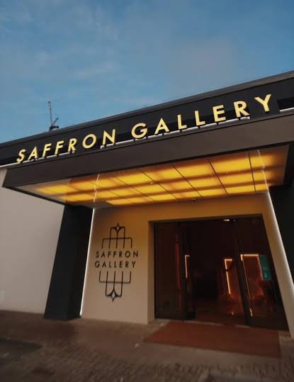 The Saffron Gallery entrance at dusk, below the illuminated gold sign.