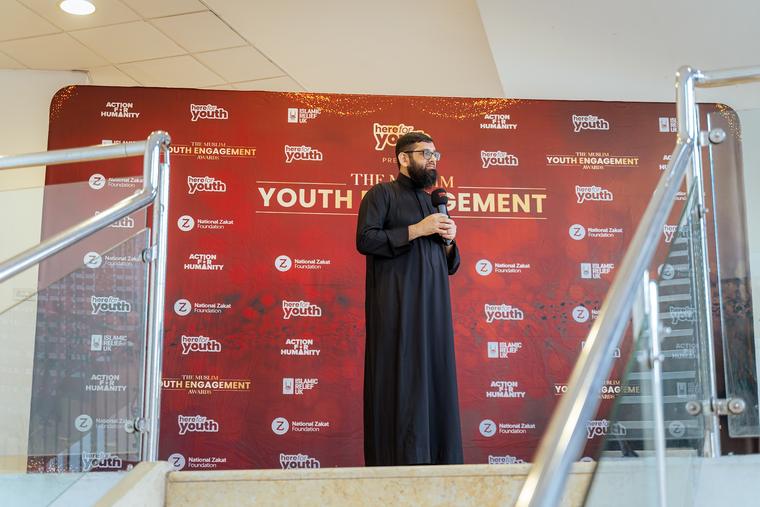 A speaker addressing the room from the stage.