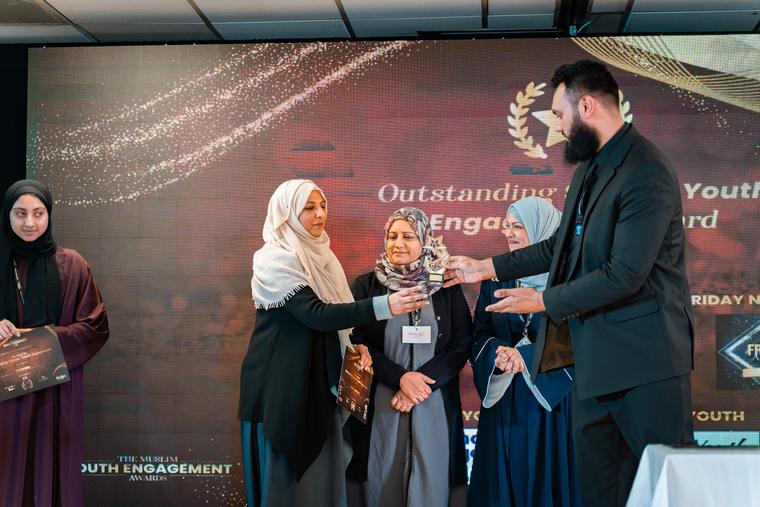 A trophy being presented to a recipient on stage.